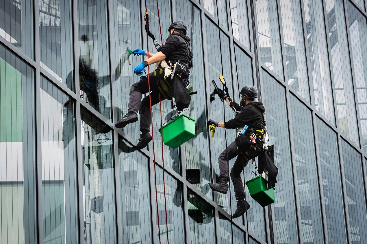 Spezialisten bei der Gebäudereinigung Berlin – Fassadenreinigung an Hochhäusern mit Sicherheitsausrüstung und Reinigungswerkzeug.