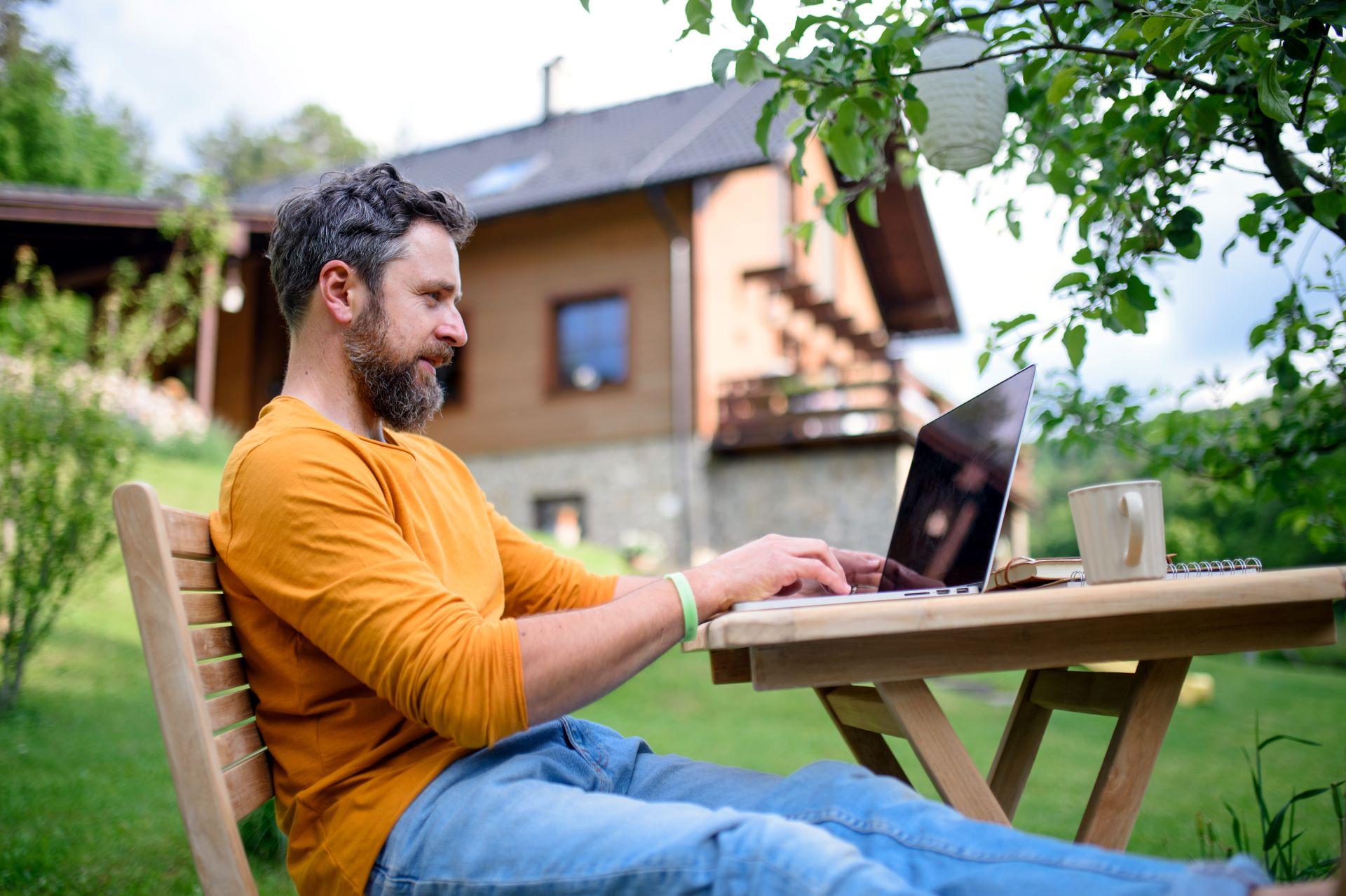 Mann arbeitet im Garten mit Laptop