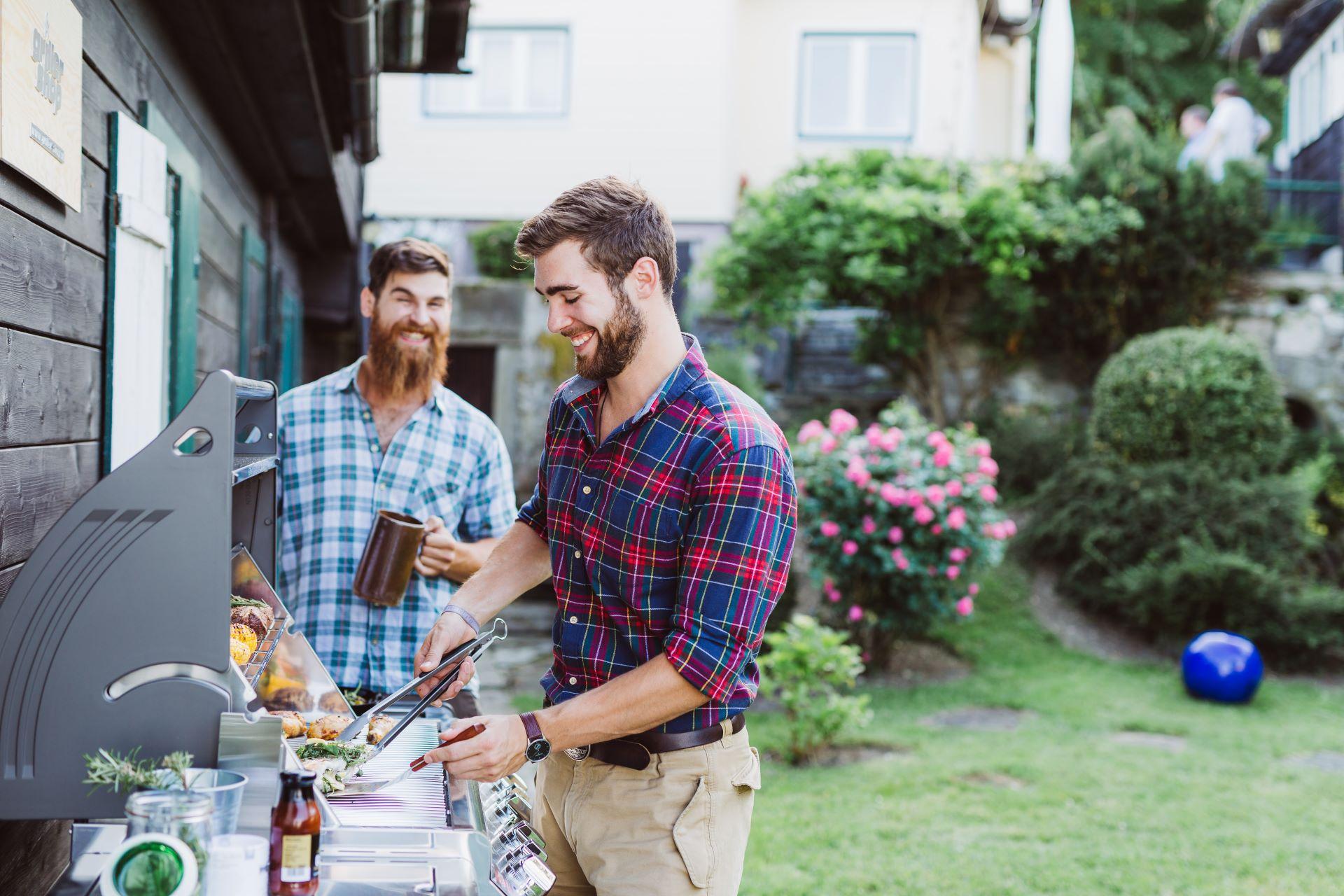 Zwei Männer grillen gemeinsam an Aussenküche