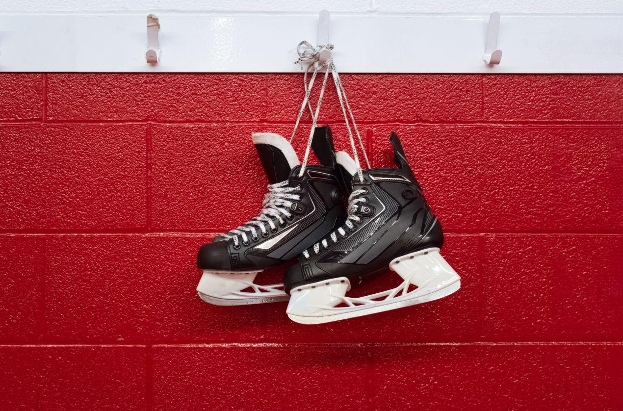 Schlittschuhe Bauer haengen an roter Wand in Eishockey-Umkleide