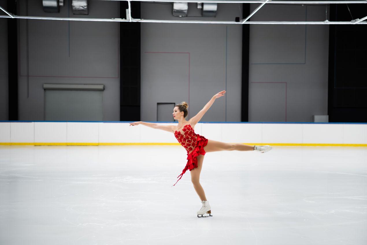 Eiskunstlaeuferin mit Schlittschuhe Bauer in rotem Kleid beim Training