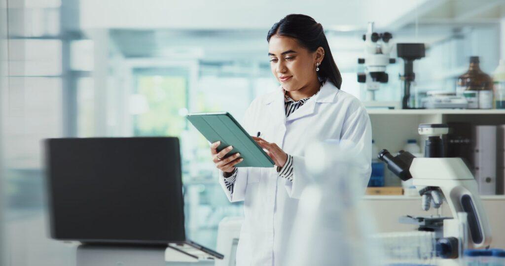 Forscherin im Labor nutzt Tablet zur effizienten Post Market Surveillance und digitalen Dokumentation in der Medizintechnik