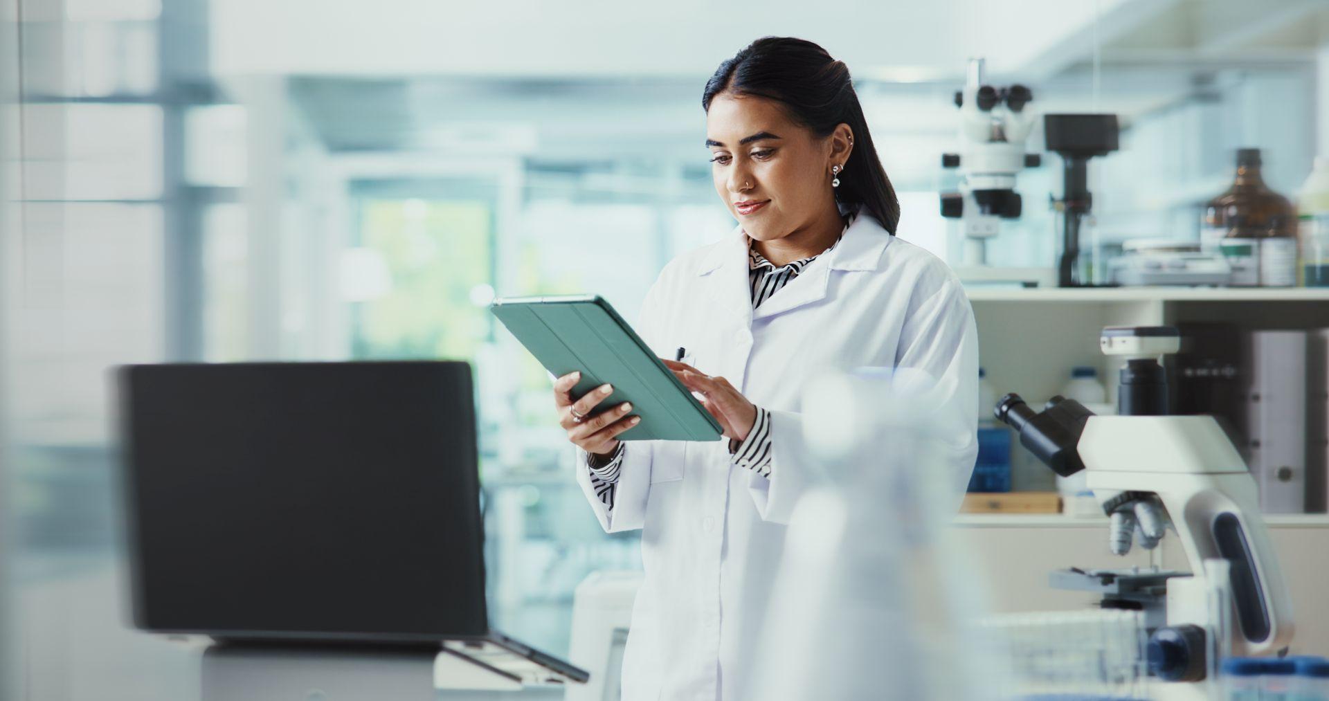 Forscherin im Labor nutzt Tablet zur effizienten Post Market Surveillance und digitalen Dokumentation in der Medizintechnik