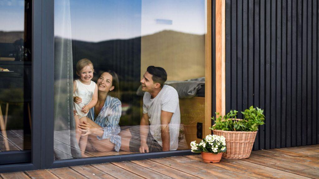 Familie sitzt geschützt hinter großer Fensterfläche mit Sichtschutz