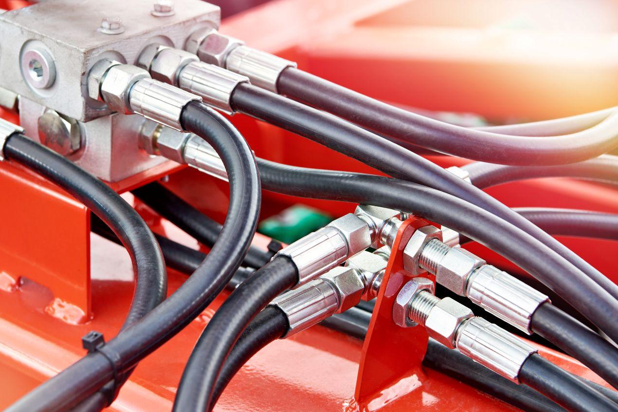 Flexible Förderschläuche in einem roten Hydrauliksystem mit Druckanschlüssen für industrielle Anwendungen