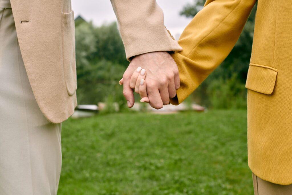 Zwei Menschen in hellen Jacken halten sich dezent an den Haenden – Symbol fuer Reduktion und emotionale Naehe ohne Pomp