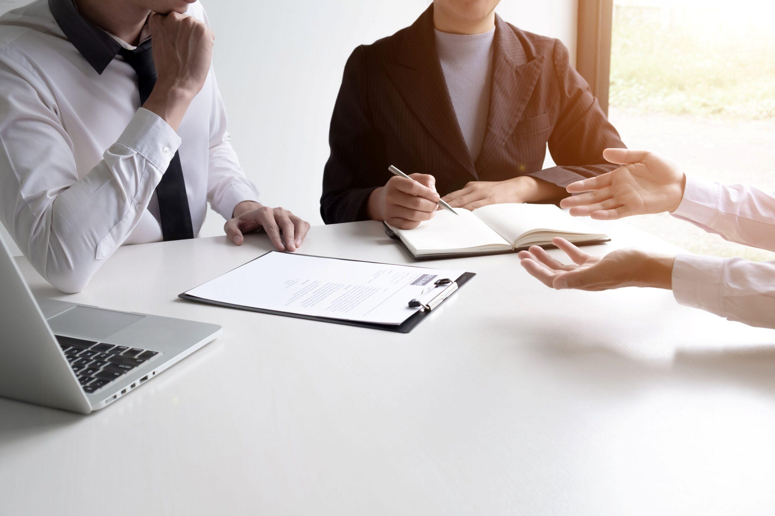 Hallenbüro Besprechung, bei der Mitarbeitende an einem Tisch Dokumente prüfen