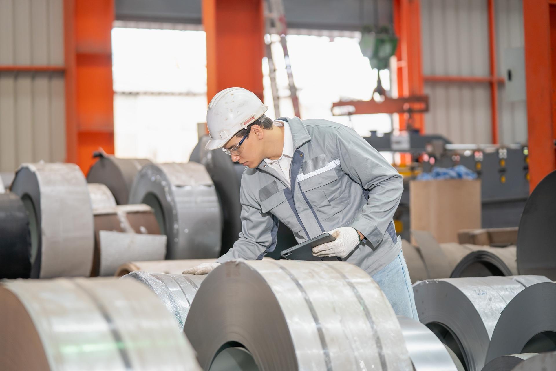 Facharbeiter prüft Metallrollen in Werkhalle | Industriesauger Staub